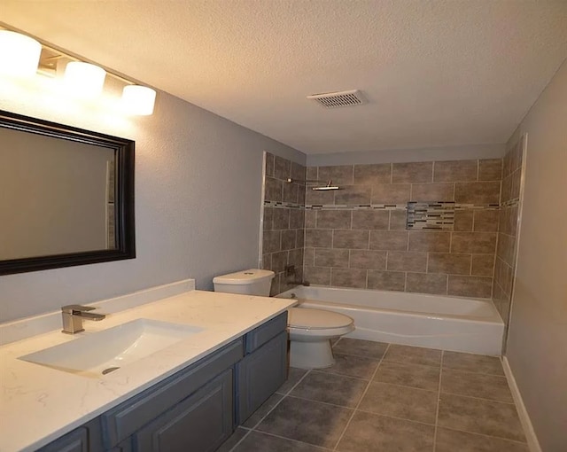 full bathroom with vanity, a textured ceiling, tiled shower / bath combo, toilet, and tile patterned floors