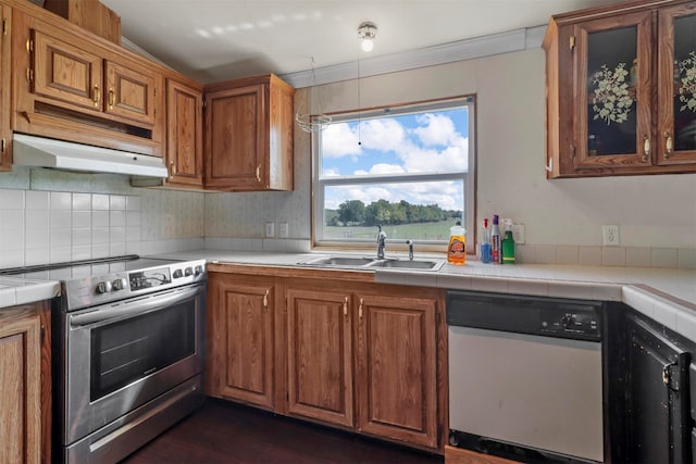 kitchen featuring sink, stainless steel electric stove, dishwashing machine, dark wood-type flooring, and tile countertops