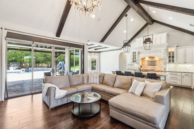 living room featuring an inviting chandelier, beam ceiling, dark wood-type flooring, and a healthy amount of sunlight