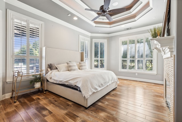 bedroom with ceiling fan, a tray ceiling, dark hardwood / wood-style floors, and ornamental molding