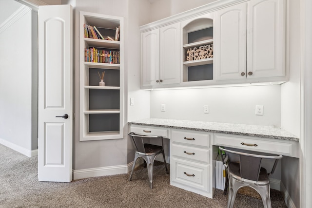 carpeted home office featuring built in desk