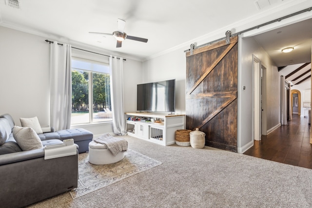 living room with crown molding, ceiling fan, hardwood / wood-style flooring, and a barn door