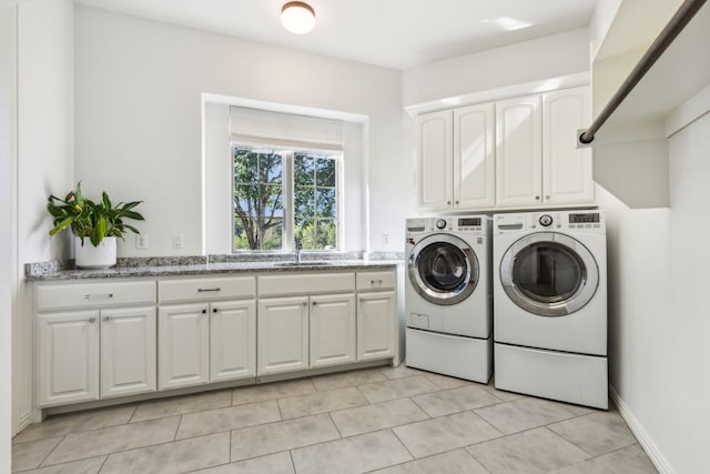 laundry room featuring separate washer and dryer, cabinets, and light tile patterned floors