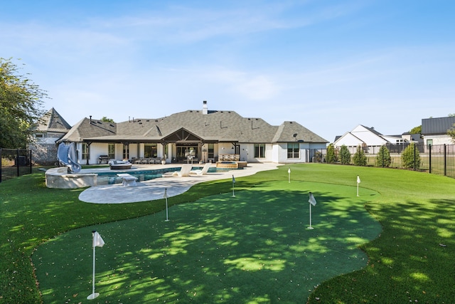 back of house featuring a fenced in pool, a lawn, and a patio