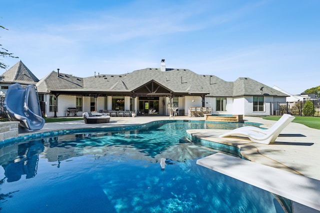 view of swimming pool with a water slide, a diving board, an in ground hot tub, and a patio area