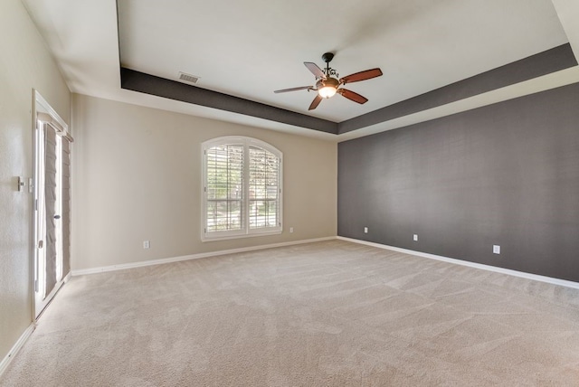 carpeted spare room featuring a raised ceiling and ceiling fan