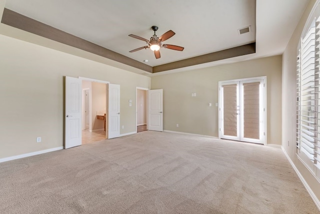 unfurnished bedroom featuring a raised ceiling, access to exterior, ceiling fan, and light colored carpet