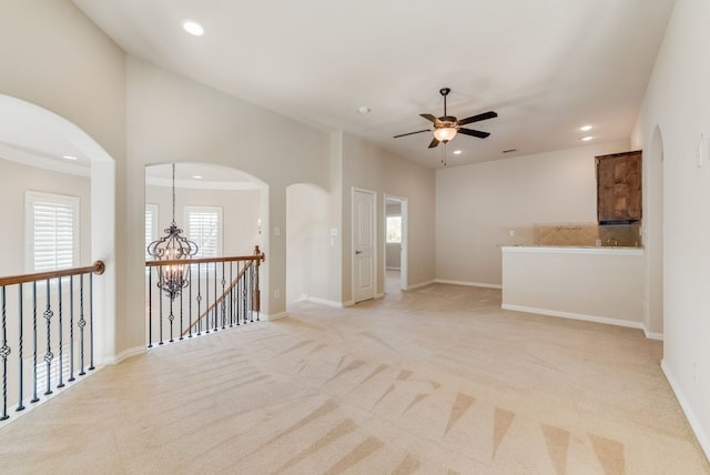 carpeted spare room with ceiling fan with notable chandelier and a healthy amount of sunlight