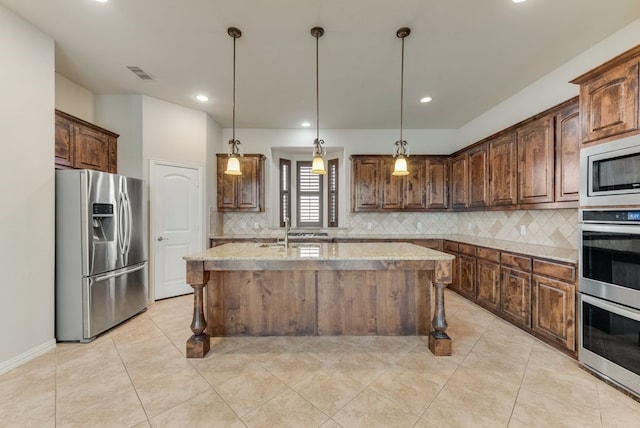 kitchen with backsplash, light stone counters, appliances with stainless steel finishes, and a kitchen island with sink