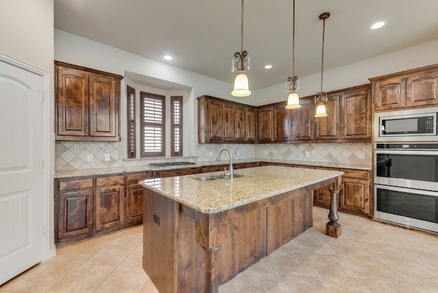 kitchen featuring backsplash, stainless steel appliances, a center island with sink, and sink