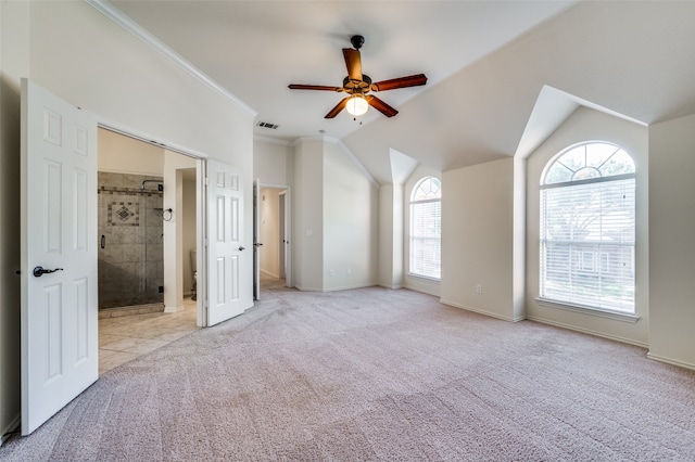 interior space with vaulted ceiling, ensuite bathroom, crown molding, light colored carpet, and ceiling fan