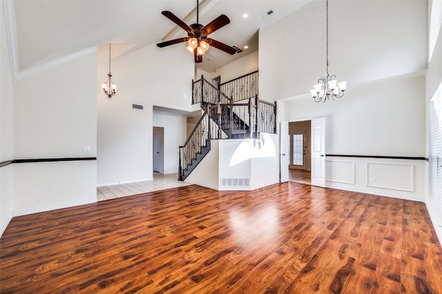 unfurnished living room featuring ceiling fan with notable chandelier, hardwood / wood-style floors, high vaulted ceiling, and beamed ceiling