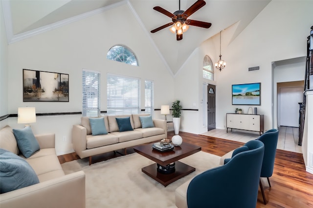 living room with ceiling fan with notable chandelier, crown molding, high vaulted ceiling, and light hardwood / wood-style floors