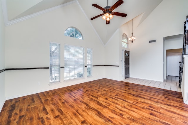 unfurnished living room with ceiling fan with notable chandelier, high vaulted ceiling, hardwood / wood-style floors, and a wealth of natural light