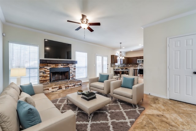 living room featuring crown molding, ceiling fan with notable chandelier, and a stone fireplace