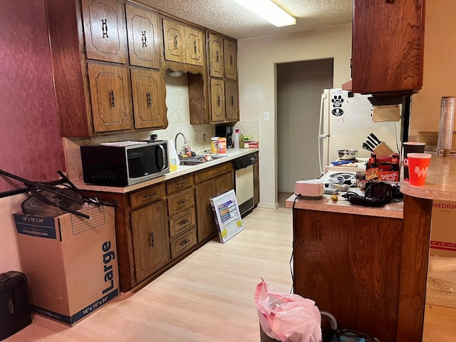 kitchen featuring light hardwood / wood-style flooring, white refrigerator, dishwasher, sink, and a textured ceiling