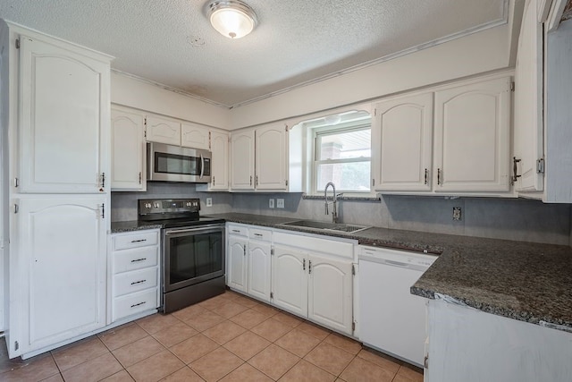 kitchen featuring appliances with stainless steel finishes, a textured ceiling, white cabinetry, a sink, and light tile patterned flooring