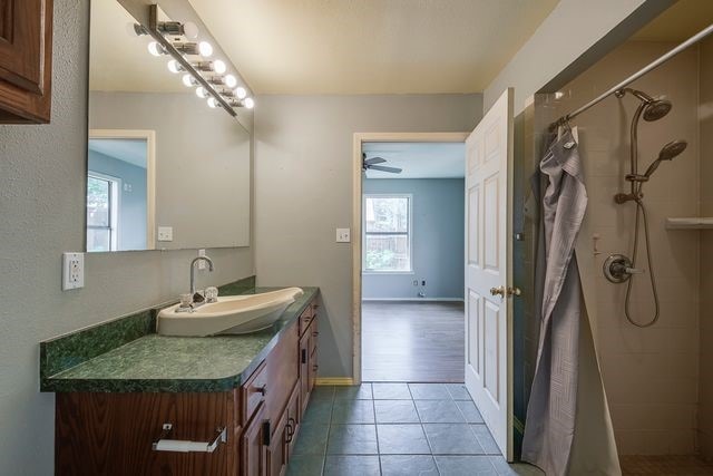 bathroom featuring baseboards, vanity, a shower stall, and tile patterned floors