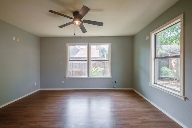 spare room featuring dark wood-style floors, plenty of natural light, and baseboards