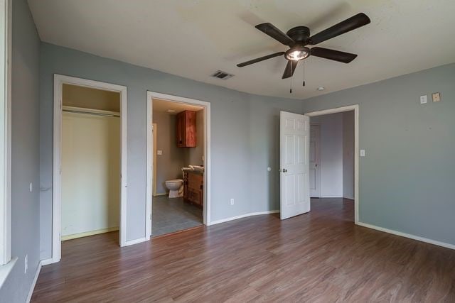 unfurnished bedroom with dark wood-style floors, baseboards, visible vents, and a closet