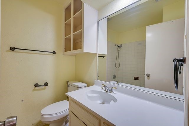 bathroom featuring toilet, a shower, and vanity