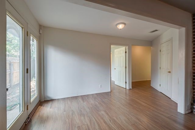 empty room featuring light wood finished floors, visible vents, and baseboards