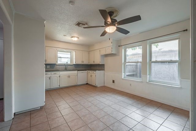 kitchen featuring white cabinets, dishwasher, ceiling fan, a textured ceiling, and a sink