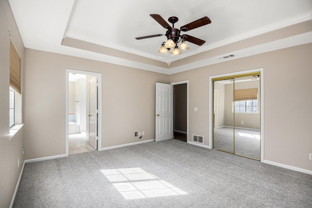 unfurnished bedroom with light colored carpet, ornamental molding, a raised ceiling, and a closet