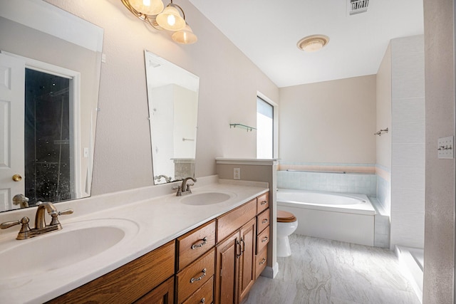 bathroom featuring a washtub, vanity, and toilet