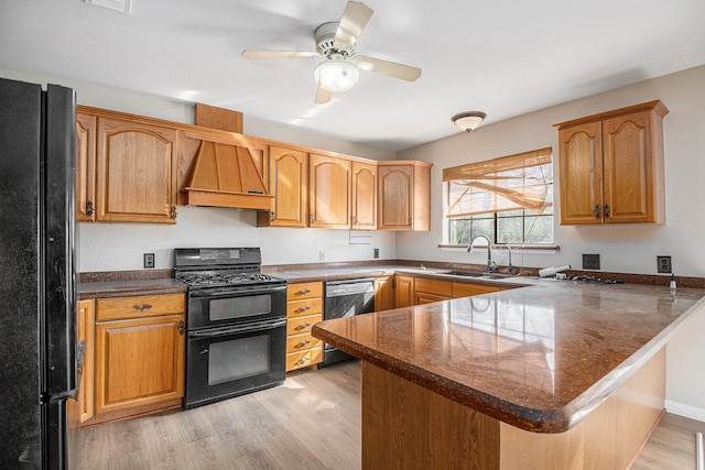 kitchen featuring kitchen peninsula, sink, light hardwood / wood-style floors, and black appliances