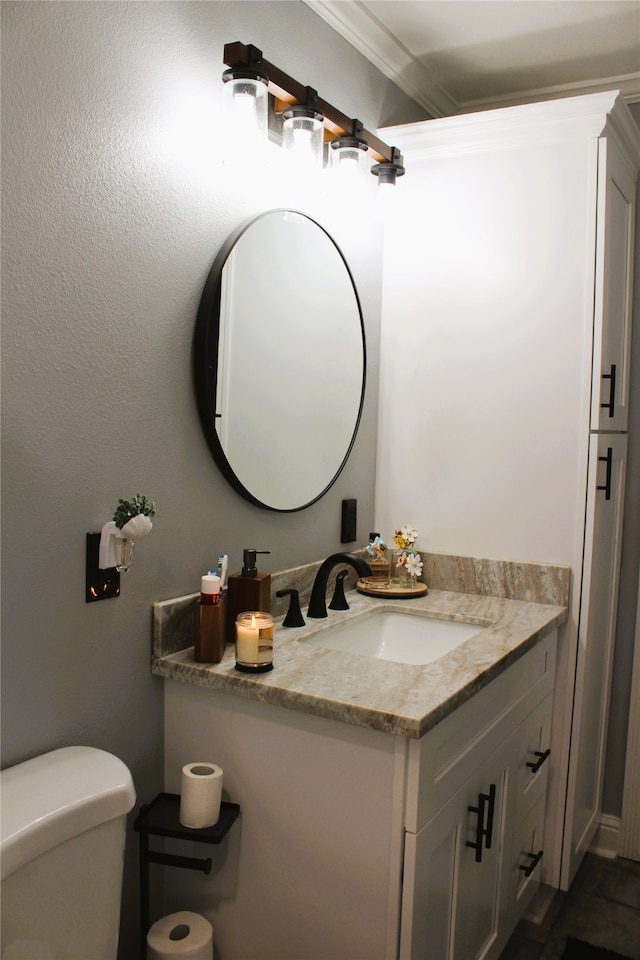 bathroom featuring toilet, ornamental molding, and vanity