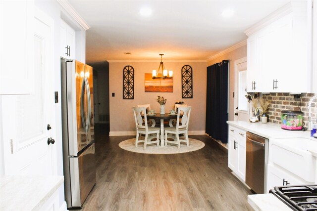 kitchen with hardwood / wood-style floors, white cabinets, stainless steel appliances, and hanging light fixtures