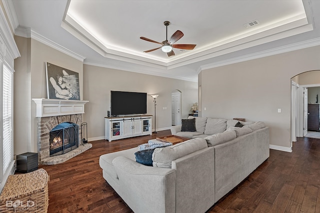 living room featuring ceiling fan, a fireplace, a raised ceiling, and dark hardwood / wood-style floors