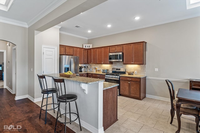 kitchen featuring appliances with stainless steel finishes, a center island, tasteful backsplash, and ornamental molding