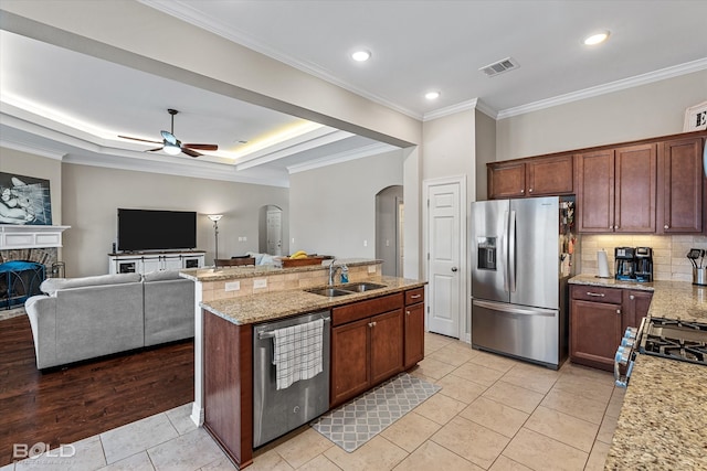 kitchen featuring stainless steel appliances, light hardwood / wood-style floors, sink, crown molding, and a stone fireplace