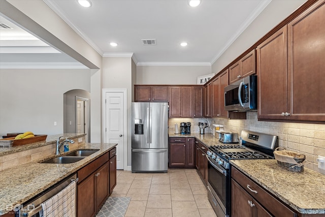 kitchen with appliances with stainless steel finishes, light stone counters, crown molding, and tasteful backsplash