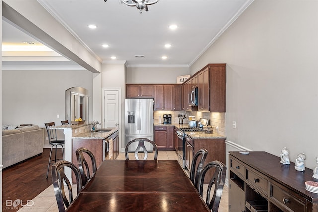 dining room with sink, light hardwood / wood-style flooring, and ornamental molding