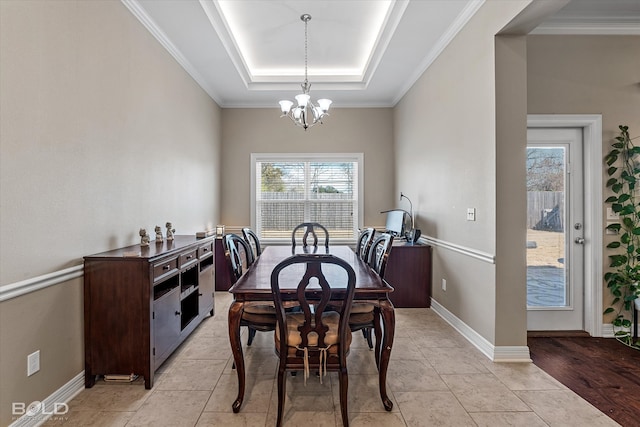 dining area featuring light wood-type flooring, a raised ceiling, a chandelier, and ornamental molding