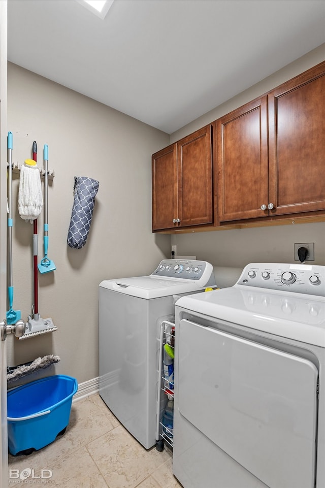 clothes washing area featuring light tile patterned floors, separate washer and dryer, and cabinets