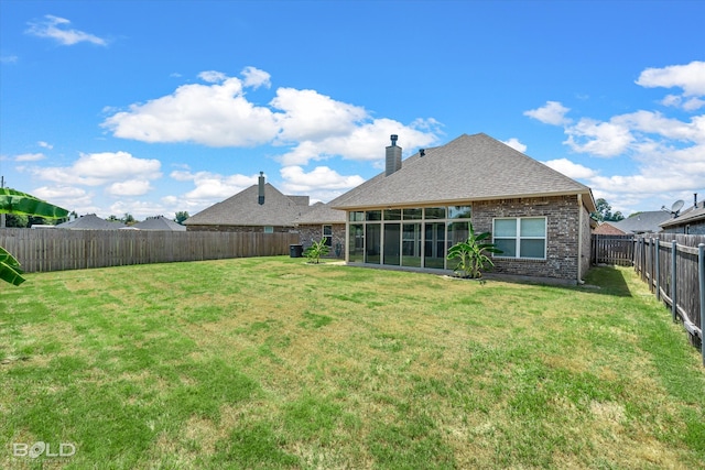 back of house featuring a sunroom and a lawn