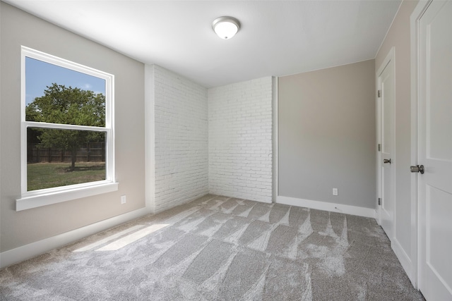 empty room featuring light colored carpet and brick wall