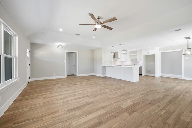 unfurnished living room with light wood-type flooring, sink, and ceiling fan