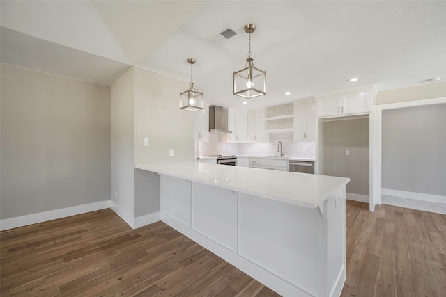 kitchen featuring wall chimney exhaust hood, dark hardwood / wood-style flooring, kitchen peninsula, stainless steel appliances, and white cabinets