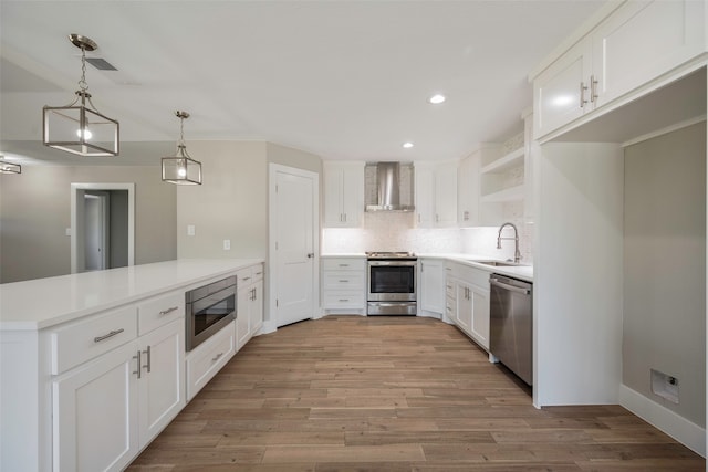 kitchen featuring light hardwood / wood-style flooring, appliances with stainless steel finishes, white cabinetry, sink, and wall chimney range hood