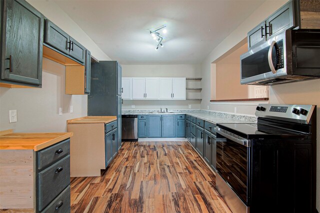 kitchen featuring light hardwood / wood-style flooring, butcher block countertops, track lighting, appliances with stainless steel finishes, and sink