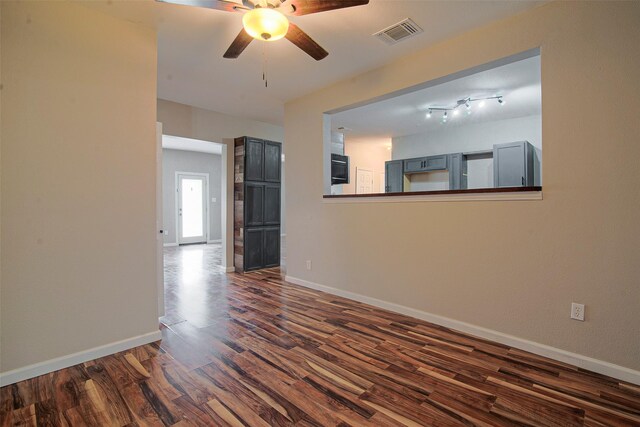 spare room with ceiling fan, rail lighting, and dark wood-type flooring