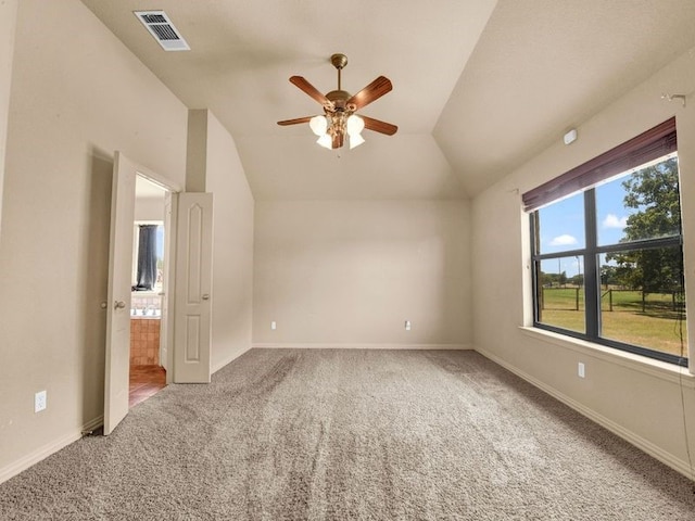 carpeted spare room with vaulted ceiling, a ceiling fan, visible vents, and baseboards