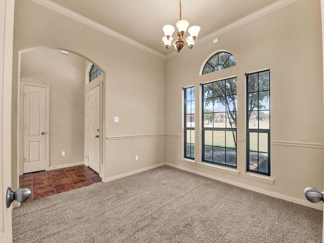 carpeted spare room featuring arched walkways, a chandelier, baseboards, tile patterned floors, and crown molding