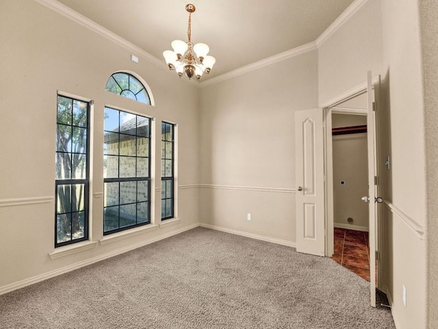 carpeted spare room with ornamental molding, a notable chandelier, and baseboards