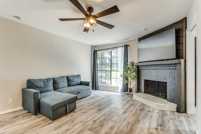 living room featuring ceiling fan, light hardwood / wood-style floors, and a brick fireplace